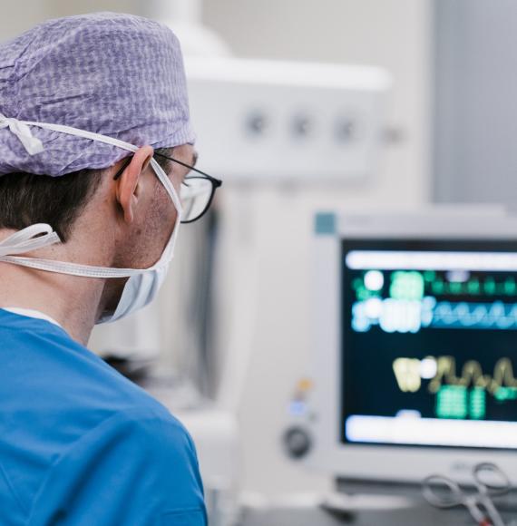 Male surgeon looking at a computer while in theatre
