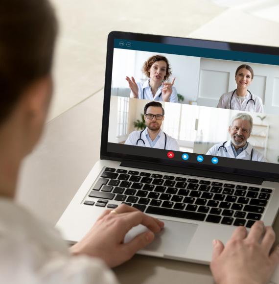 Doctor using a laptop to communicate virtually with colleagues