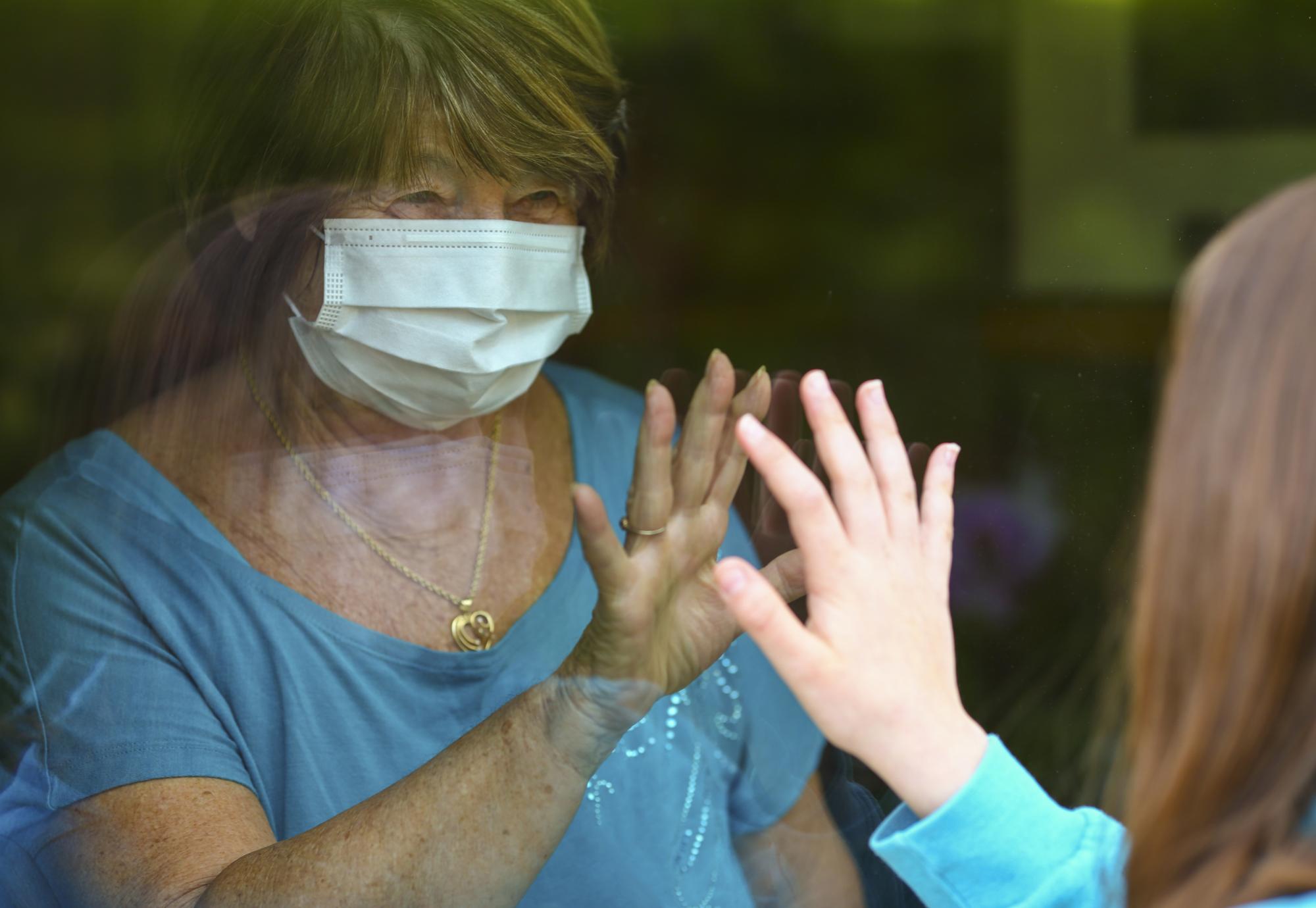 Elderly woman being visited by family during a pandemic