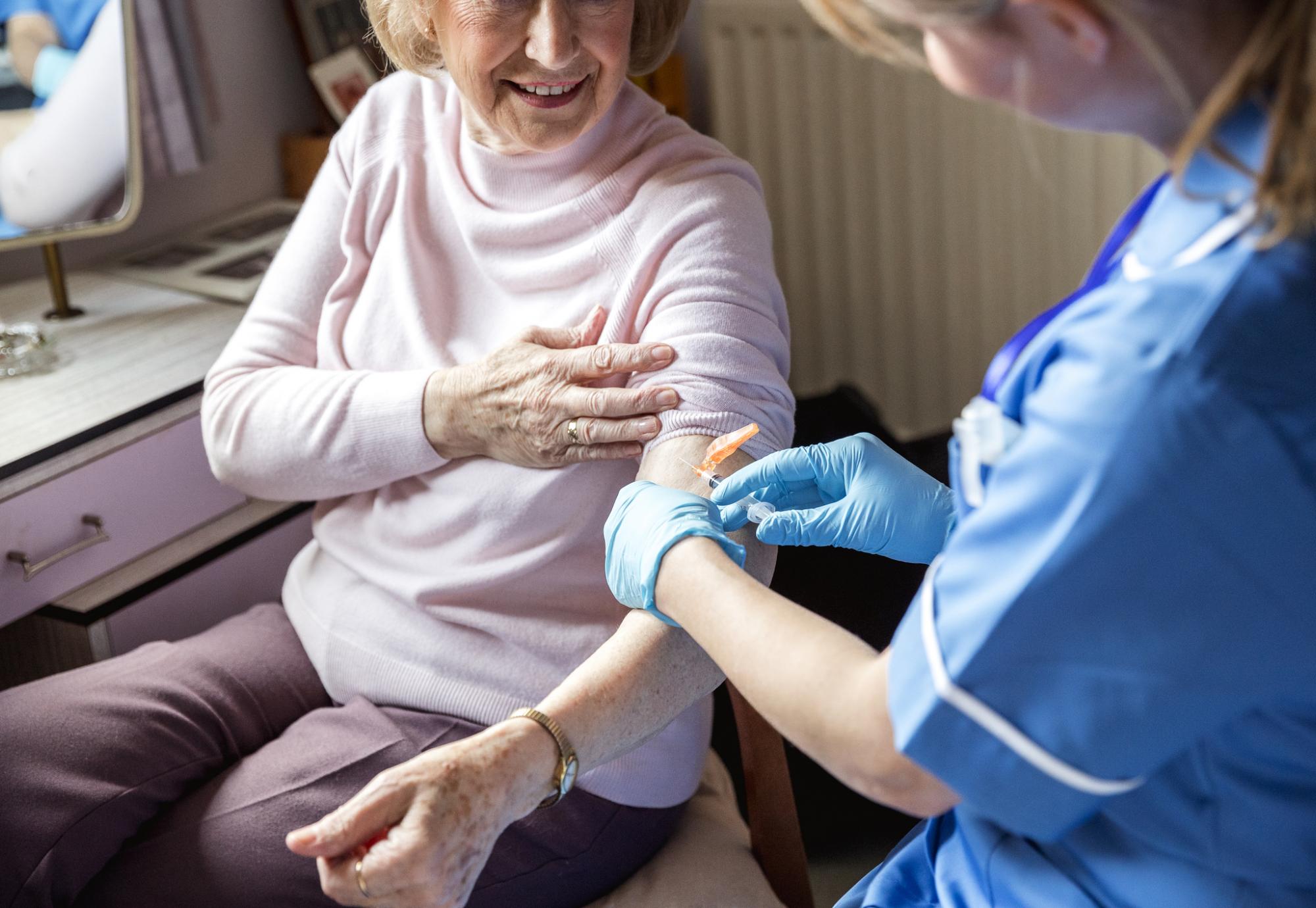 Elderly woman getting the flu jab in her home