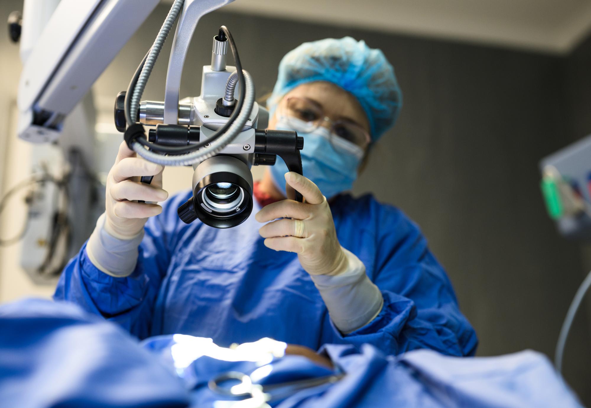 Female doctor positioning microscope in operating theatre