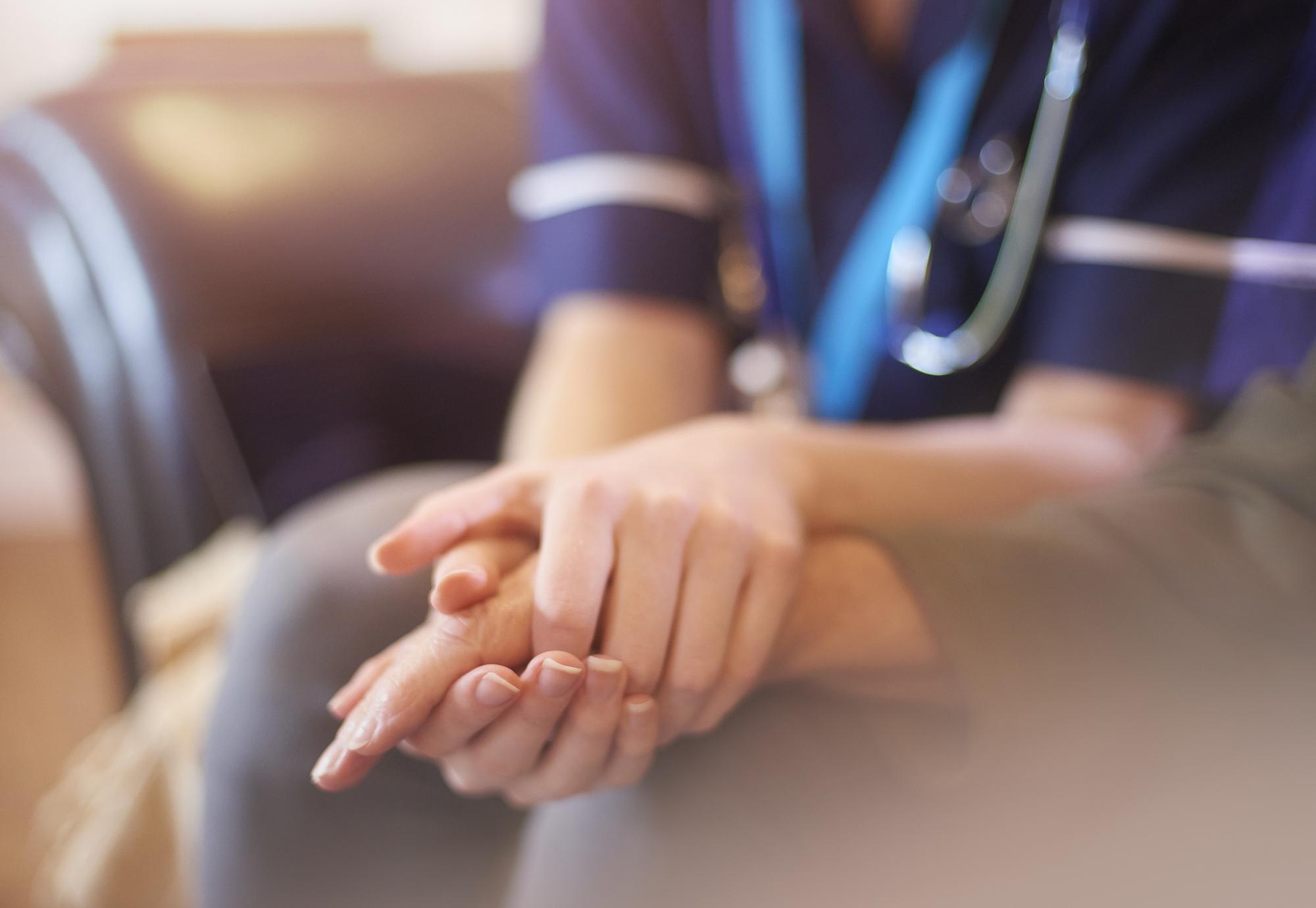 A female nurse consoles a senior patient