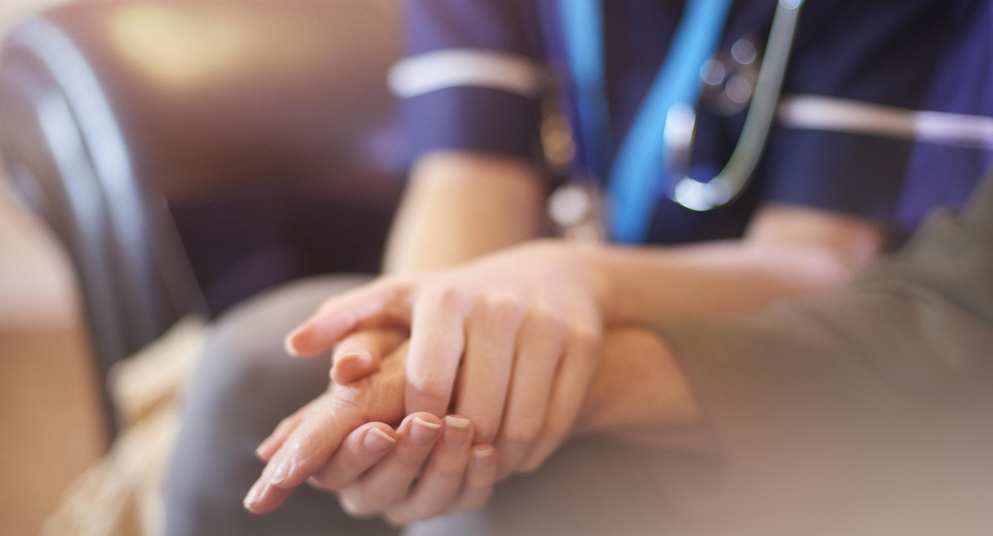 A female nurse consoles a senior patient