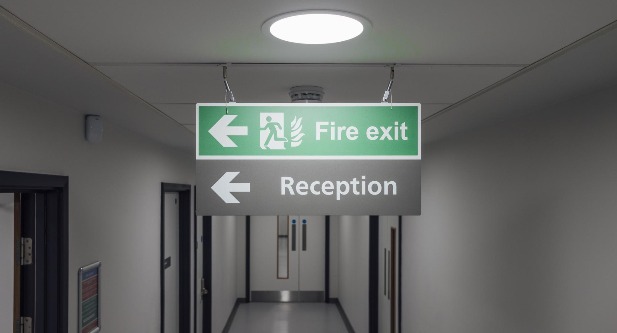 fire exit sign hanging from the ceiling in a hospital