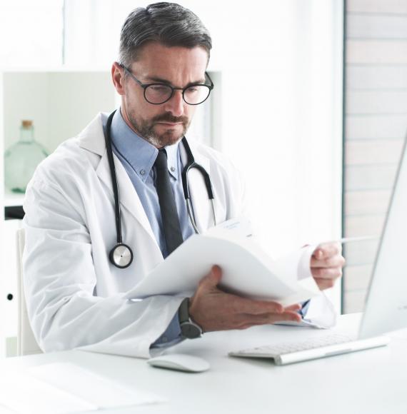 Male doctor reviewing paperwork at his desk