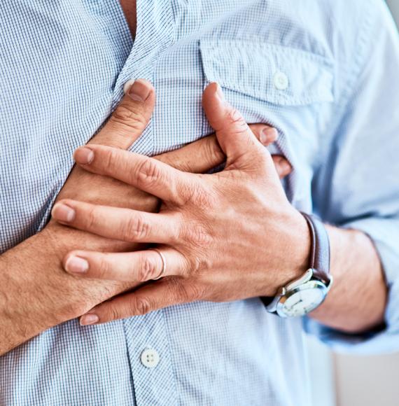 Man clutching his chest because of heart attack symptoms