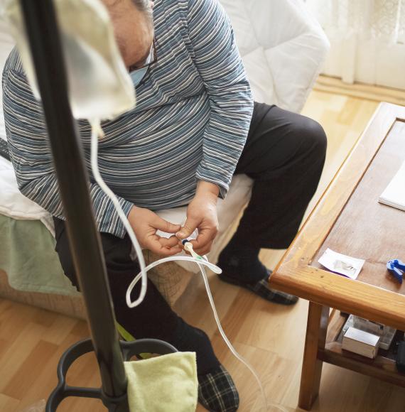 Senior man connecting peritoneal dialysis with catheter at home