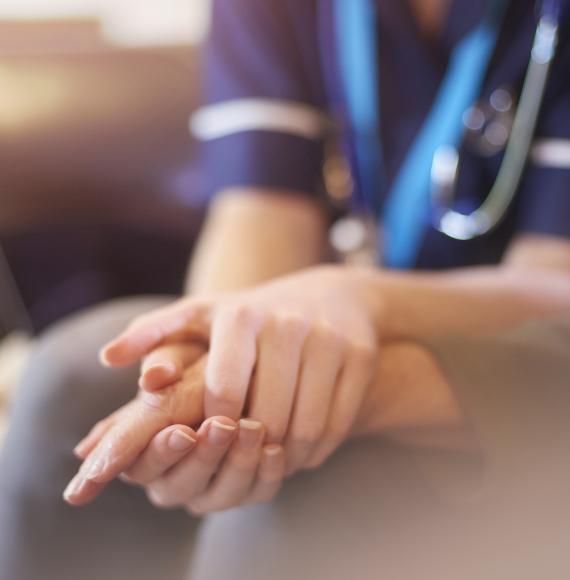 A female nurse consoles a senior patient