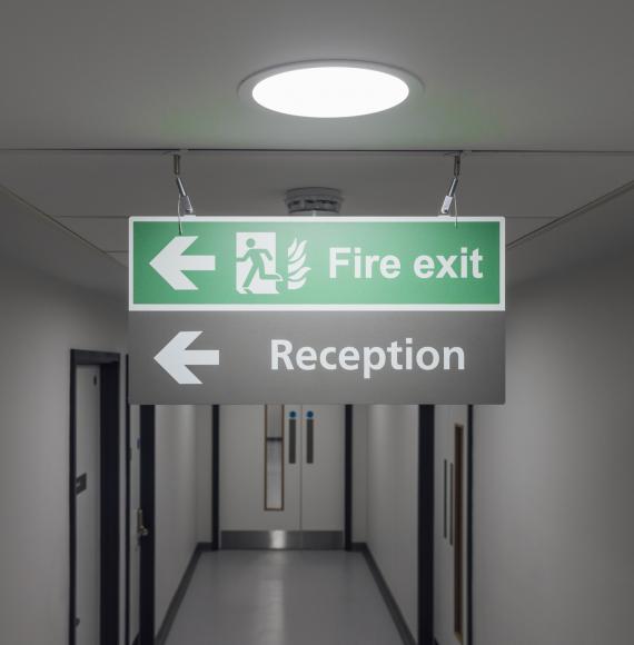 fire exit sign hanging from the ceiling in a hospital